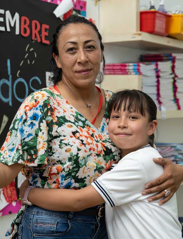 A student hugging a teacher at Christel House Mexico