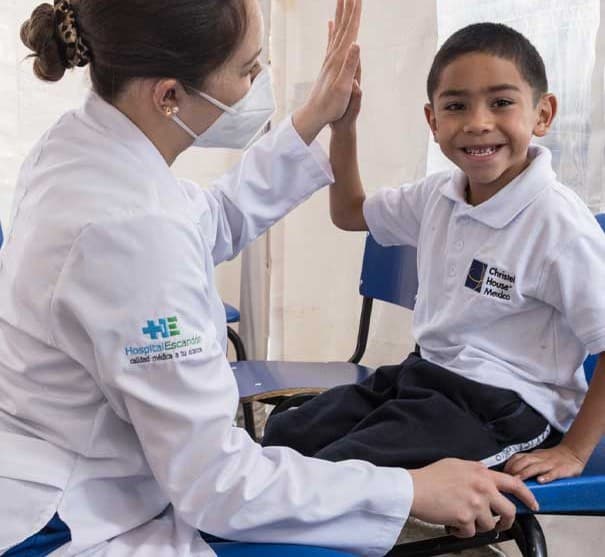A school nurse high fiving a student at Christel House Mexico