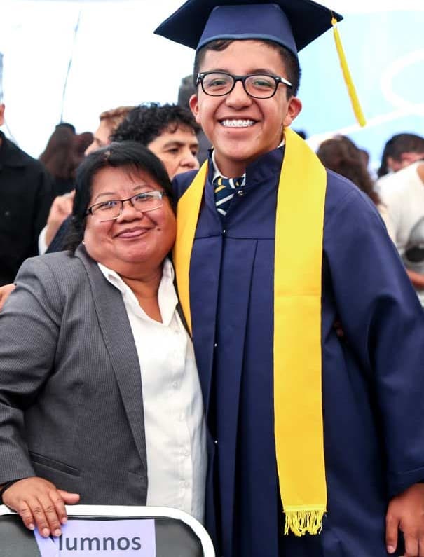 A student wearing a cap and gown with a teacher